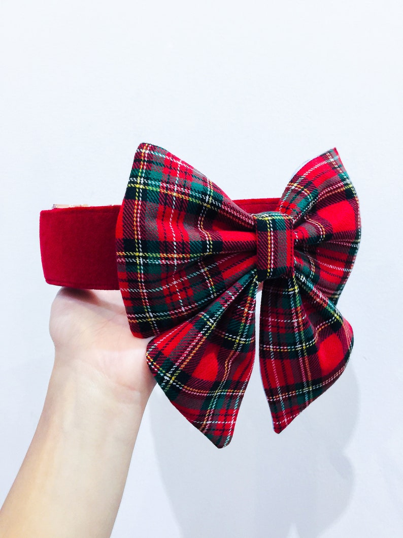 May include: Red velvet headband with a large plaid bow. The bow is made of red, green, and yellow plaid fabric.