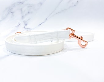 May include: White dog leash with a rose gold metal clip.