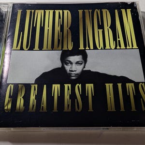 May include: A Luther Ingram "Greatest Hits" CD case. The album cover features the artist's name in gold lettering above a black and white photo of the singer. The words "Greatest Hits" are in gold lettering below the photo.