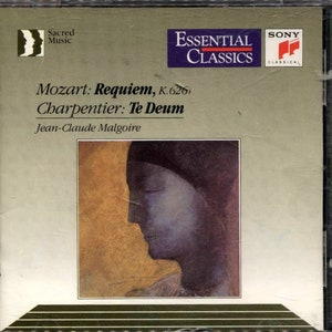 May include: A CD case with the "Essential Classics" label. The artwork displays a profile portrait in blue and gold tones. The text on the cover reads "Mozart: Requiem, K.626, Charpentier: Te Deum" and "Jean-Claude Malgoire."