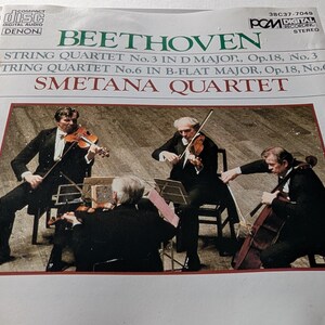 May include: A CD case featuring a photograph of the Smetana Quartet performing. The cover includes the text "BEETHOVEN" and details of the string quartets. The image shows four musicians in formal attire playing their instruments.