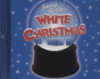 May include: A CD case featuring the musical "Irving Berlin's White Christmas." The cover art displays a snow globe design with the title in red and white lettering. The background is blue with white snowflake accents.