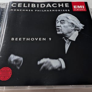 May include: A CD case with a black cover, displaying the text "CELIBIDACHE" and "BEETHOVEN 9". The cover features a portrait of a man and the EMI Classics logo. The CD is housed in a clear plastic jewel case.