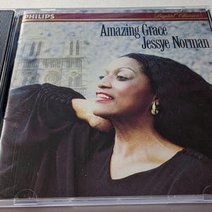 May include: A CD case featuring the album "Amazing Grace" by Jessye Norman. The cover art displays a portrait of Jessye Norman with a church in the background. The Philips logo is visible at the top left.