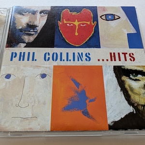May include: A Phil Collins Hits music CD in a clear plastic jewel case. The cover features a grid of six artistic panels with painted portraits, a red mask-like face, a blue eye, and an abstract blue shape on an orange background.