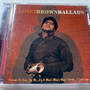 May include: A CD case featuring James Brown's album "Ballads." The cover art showcases a sepia-toned image of James Brown in a dark jacket, holding a rolled paper. The album title is at the top, with song titles at the bottom.