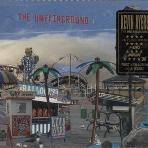 May include: Album cover for "The Unfairground" by Kevin Ayers. The artwork depicts a vintage amusement park scene with a Ferris wheel, palm trees, and various carnival game booths. The album title and artist name are displayed prominently.