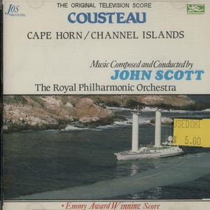 May include: A CD case featuring the original television score for "Cousteau: Cape Horn/Channel Islands." The cover displays a white ship on the water, with text including "John Scott" and "The Royal Philharmonic Orchestra." The cover also has a yellow price sticker.