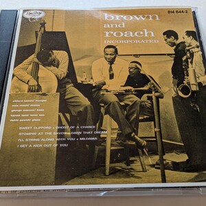 May include: A compact disc case featuring a sepia-toned photograph of a jazz ensemble. The cover text reads brown and roach INCORPORATED, along with a list of musicians and song titles including SWEET CLIFFORD and I GET A KICK OUT OF YOU.