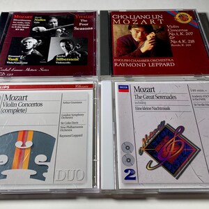 May include: Four classical music CDs featuring works by Mozart and Vivaldi. The CD cases are clear plastic with colorful artwork and text. Titles include "The Four Seasons" and "Violin Concertos."