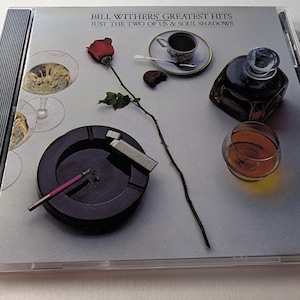 May include: A white ceramic mug with a black handle and the text "But First, Coffee" in a black, bold font. The mug is on a white surface.