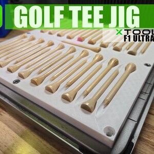 Könnte beinhalten: Ein weißer Kunststoff-Jig mit einer Reihe von hölzernen Golfschlägern. Der Jig ist mit "GOLF TEE JIG" und "XTOOL F1 ULTRA" beschriftet.