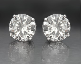 May include: A pair of silver stud earrings with large, clear, round, faceted gemstones.