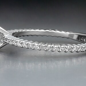 May include: A silver ring with a single diamond set in the center and a row of smaller diamonds around the band. The band is textured and marked "14K".
