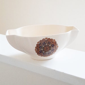 以下が含まれることがあります： 茶色と青色の花柄が施された白い陶器製のグレービーボート