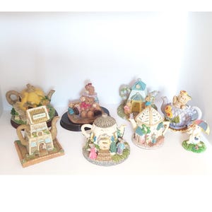 Peut inclure: Une collection de huit théières miniatures, chacune avec un design unique. Les théières sont en céramique et présentent diverses couleurs et motifs, notamment le jaune, le bleu, le vert et le brun. Certaines théières ont un design en forme de maison, tandis que d'autres présentent des ours en peluche ou d'autres personnages fantaisistes.