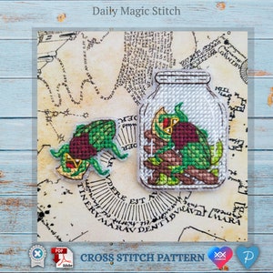 May include: Cross stitch pattern for a green and red beetle in a glass jar. The pattern is on a vintage map background with the words "Daily Magic Stitch" at the top.