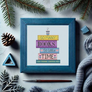 May include: A framed cross-stitch design featuring a stack of colorful books with the text "So many books, so little time." The design is framed in a teal blue frame.