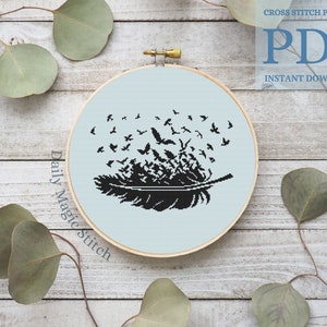 Puede incluir: Patrón de punto de cruz en blanco y negro de una pluma con pájaros volando fuera de ella. El patrón está en un aro de bordado azul claro sobre un fondo de madera. El texto "Daily Magic Stitch" está escrito en el lado izquierdo del aro. El texto "CROSS STITCH PATTERN PDF INSTANT DOWNLOAD" está escrito en la esquina superior derecha de la imagen.