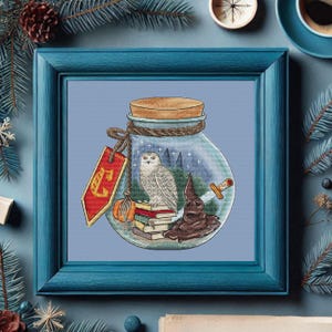 May include: A glass jar with a blue rope lid and a white owl, a brown hat, a sword, and books inside. The jar has a red tag with the letter "E" on it.