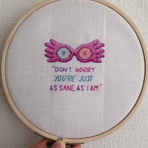 Puede incluir: Arte de bordado en aro con un par de gafas rosas y una cita que dice "No te preocupes, est&aacute;s tan cuerdo como yo."