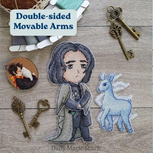 May include: Cross-stitch figures of a character with long black hair and a blue deer with white wings. The figures are on a wooden surface with antique keys and embroidery floss. The text "Double-sided Movable Arms" is in a blue box.