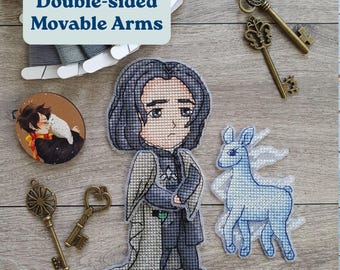 May include: Cross-stitch figures of a character with long black hair and a blue deer with white wings. The figures are on a wooden surface with antique keys and embroidery floss. The text "Double-sided Movable Arms" is in a blue box.