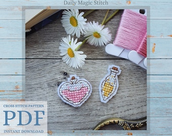 May include: Two cross stitch patterns of potion bottles on a wooden surface. One bottle is heart shaped and pink, the other is a tall bottle with a yellow liquid and white stars. The text "Daily Magic Stitch" is at the top of the image.