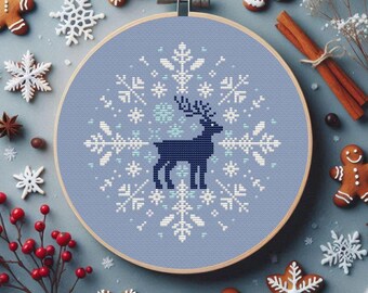 May include: A blue and white cross-stitch pattern of a reindeer standing in a circle of snowflakes. The design is framed in a wooden hoop.