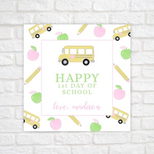 May include: A square print with a white background featuring a yellow school bus, pencils, and pink and green apples. The text reads "HAPPY 1st DAY OF SCHOOL" and "love, madison" in a pink font.
