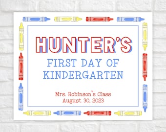 May include: A white sign with a blue border and colorful crayon illustrations. The text reads "HUNTER'S FIRST DAY OF KINDERGARTEN" with the name in red and the rest in blue. Below the text is "Mrs. Robinson's Class August 30, 2023".