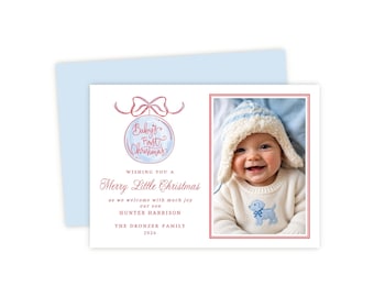 May include: A rectangular holiday card featuring a light blue envelope, a red-outlined photo of a smiling infant in a knit hat and sweater, and text reading Baby's First Christmas, Merry Little Christmas, Hunter Harrison, The Dronzek Family 2026.