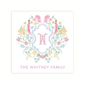 May include: A watercolor illustration of a floral wreath with a blue and white crest in the center. The crest features the letter "W" in pink. The text "THE WHITNEY FAMILY" is written below the wreath.