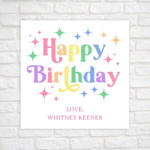 May include: A white card with the text "Happy Birthday" in rainbow colors and surrounded by sparkling stars. The card also includes the text "LOVE, WHITNEY KEENER".