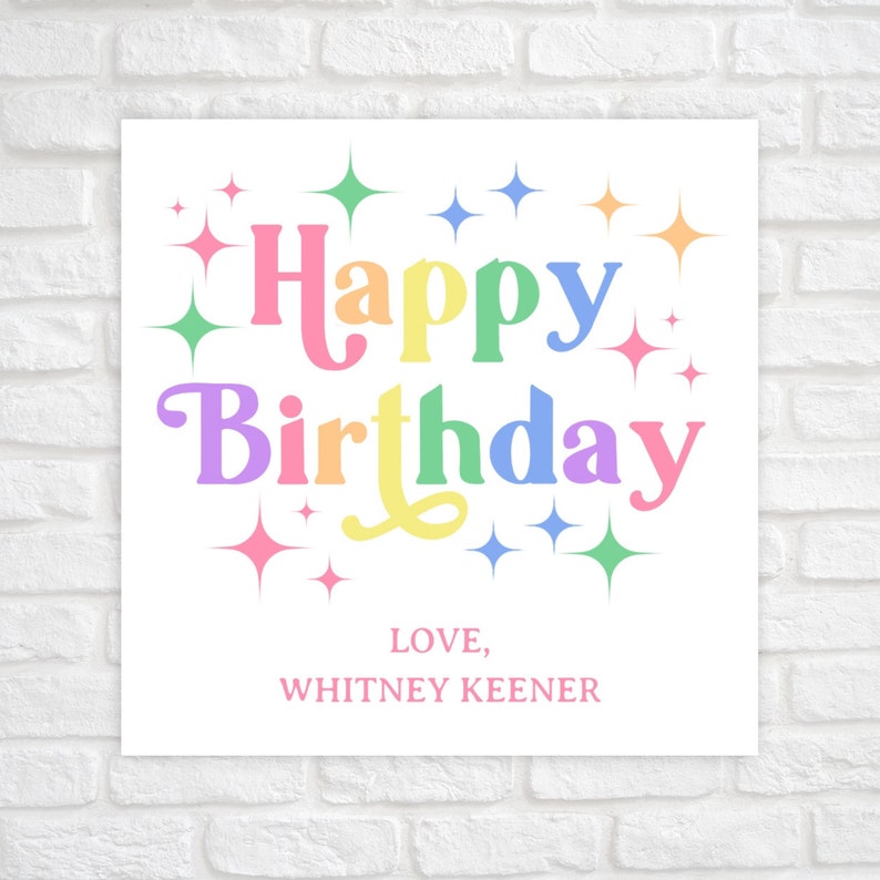 May include: A white card with the text "Happy Birthday" in rainbow colors and surrounded by sparkling stars. The card also includes the text "LOVE, WHITNEY KEENER".