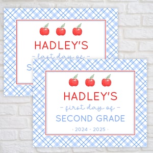 May include: Two signs with a blue and white checkered background. The top sign says "HADLEY'S - last day of -" with three red apples. The bottom sign says "HADLEY'S - first day of - SECOND GRADE 2024-2025." with three red apples.