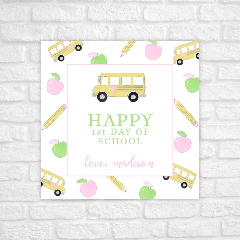 May include: A square print with a white background featuring a yellow school bus, pencils, and pink and green apples. The text reads "HAPPY 1st DAY OF SCHOOL" and "love, madison" in a pink font.