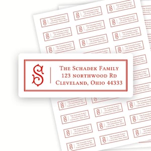 May include: Sheets of personalized address labels. Each label features the text "The Schadek Family, 123 Northwood Rd, Cleveland, Ohio 44333" in a red font, along with a stylized "S" initial. The labels are rectangular with a white background.