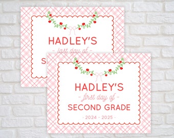 May include: Two rectangular signs with a pink and white plaid border and a scalloped red edge. The signs feature a green vine with red berries and a pink bow at the top. Text reads HADLEY'S last day of and HADLEY'S first day of SECOND GRADE 2024-2025.