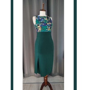 May include: A sleeveless dress with a floral print top and a solid green skirt. The skirt has a slit on the side.