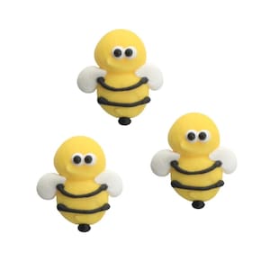 May include: Three yellow bee-shaped embellishments with black stripes and small white wings. Each bee has two black eyes and a black stinger. The bees are arranged on a white background.