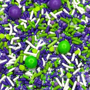 May include: A mix of green, purple and white sprinkles with small round sprinkles and long, thin sprinkles. There are also larger round sprinkles in green and purple.