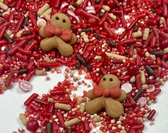 May include: Red, white, and brown sprinkles with gingerbread man shapes. The sprinkles are scattered on a white background.