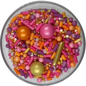 May include: A bowl of colorful sprinkles with pink, orange, and gold sprinkles, and pink, orange, and gold balls.