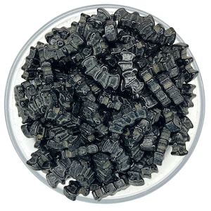 May include: A bowl filled with black bat-shaped sprinkles. The sprinkles are shiny and have a slightly textured surface.