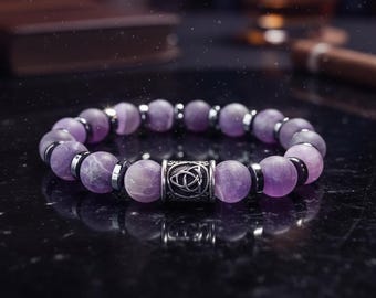 May include: A beaded bracelet featuring round, matte purple amethyst stones alternating with small, flat, metallic silver-toned spacers. A central cylindrical silver-toned bead displays an engraved triquetra knot design on its surface.