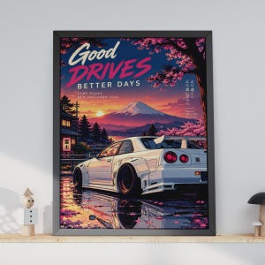 Könnte beinhalten: Ein gerahmtes Poster mit einem weißen Sportwagen auf einer nassen Straße mit Kirschblüten, dem Berg Fuji im Hintergrund sowie dem Text Good DRIVES BETTER DAYS, SAME ROADS NEW HORIZONS und japanischen Schriftzeichen am blau-rosa Himmel.