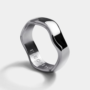 May include: A silver ring with a wavy, irregular shape. The ring is engraved with the word "ELECATT0".