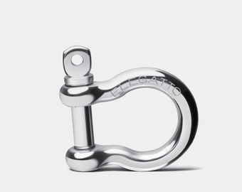 Könnte beinhalten: Ein silberner D-Ring aus Metall mit glattem, geschwungenem Design. Der Ring ist mit dem Wort "ELGATTTO" graviert.