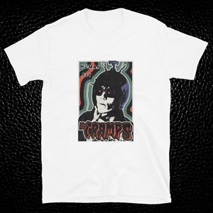 May include: White t-shirt with a vintage-style graphic of a person wearing a helmet and goggles with the text "Human Fly" and "The Cramps" printed on the front.